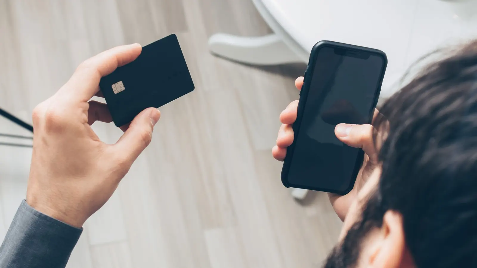 Une main tient un téléphone et une carte plastique côte à côte