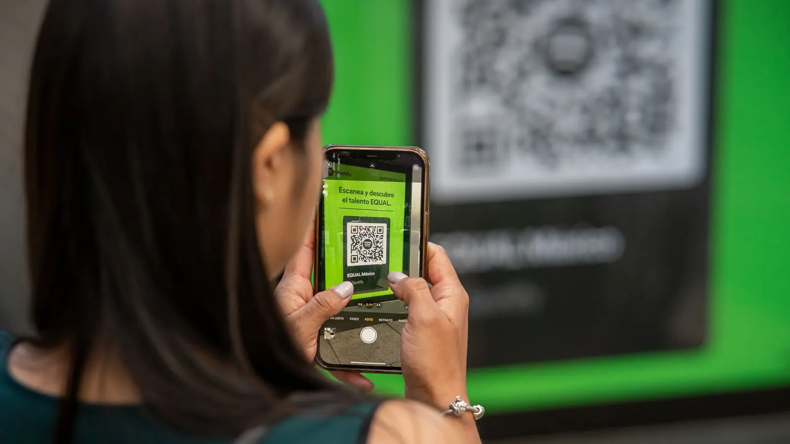 Une cliente scanne un QR code affiché dans un commerce avec son téléphone